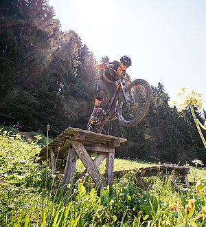 Bikerin beim Sprung in sommerlicher Landschaft