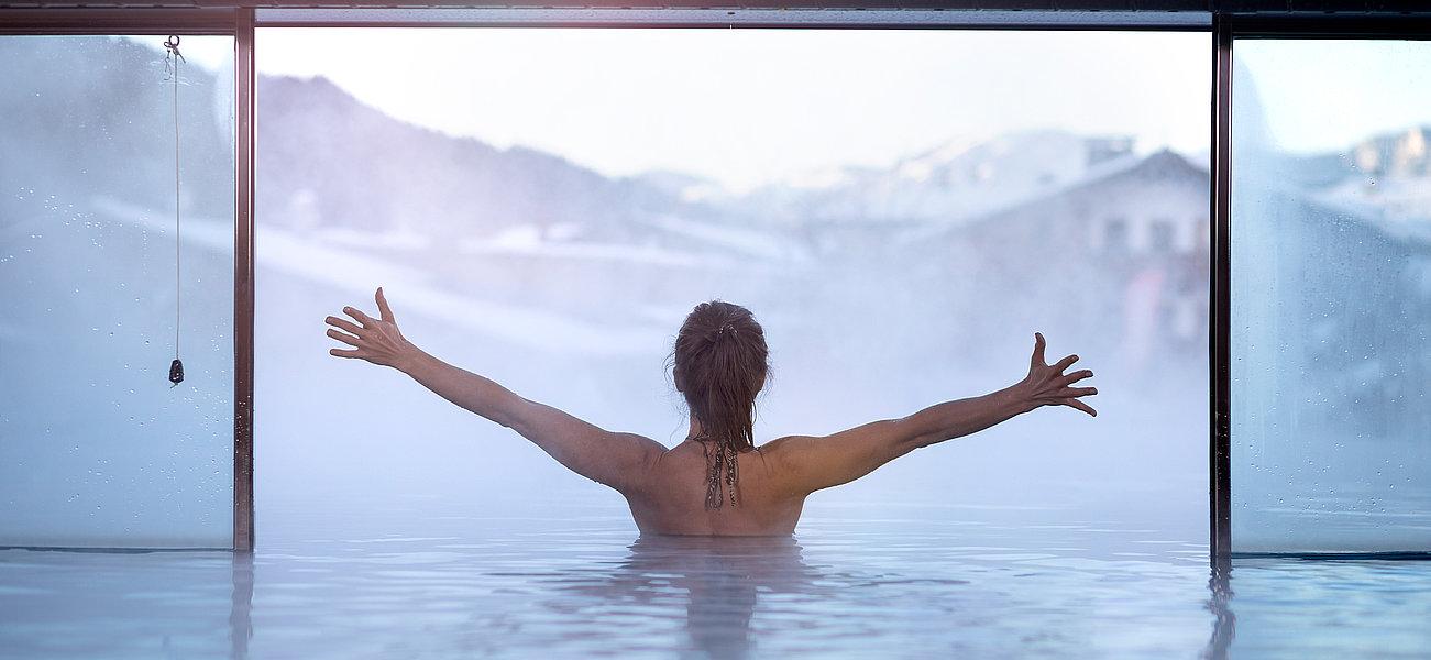 Frau genießt die Aussicht vom Innenpool aus