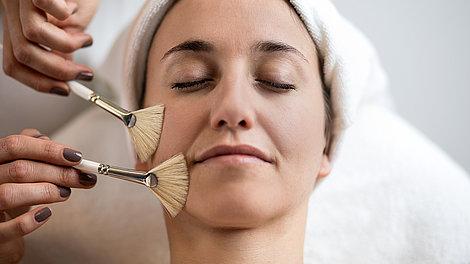 Kosmetikanwendung bei einer Frau im Gesicht