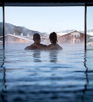 Pärchen im Innenpool sieht durch das Panoramafenster nach draußen