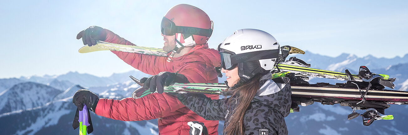 Skifahrer genießen die Aussicht mit geschulterten Skiern