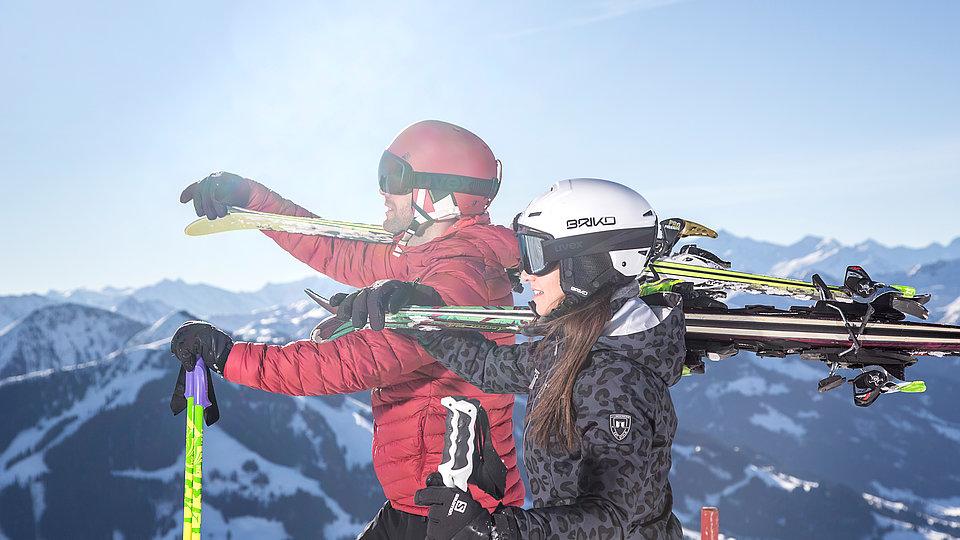 Skifahrer genießen die Aussicht mit geschulterten Skiern