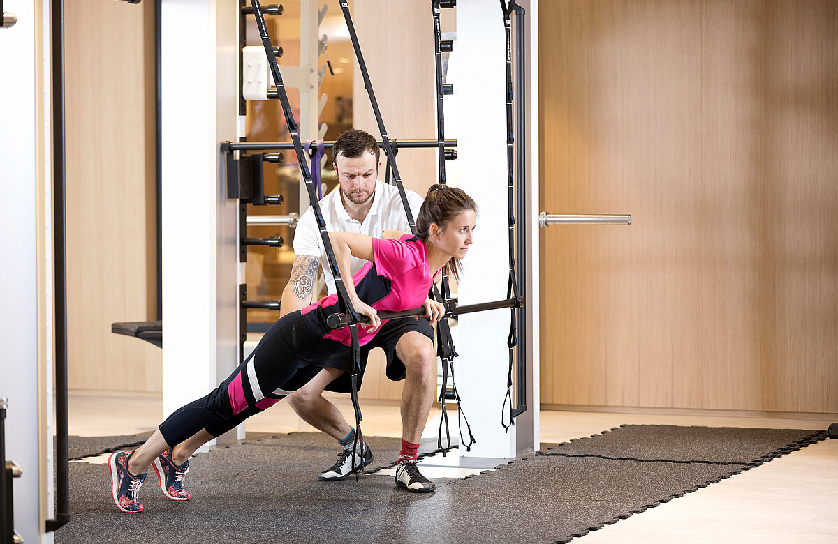 Trainer zeigt einem Gast eine Fitnessübung 